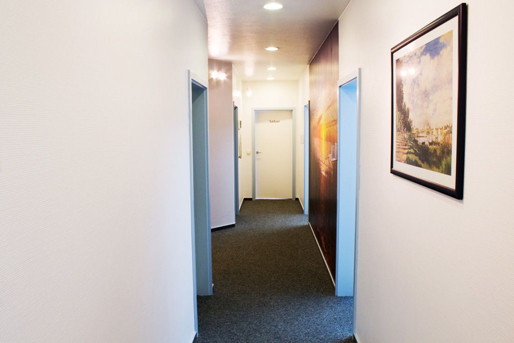 Einblicke in unsere Praxisräume in Saterland - Flur mit Bildern an der Wand